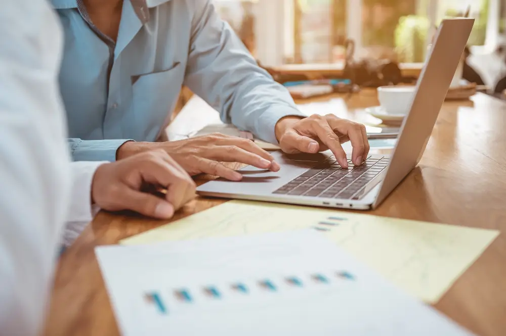 Profissionais analisando documentos e notebook em ambiente de trabalho