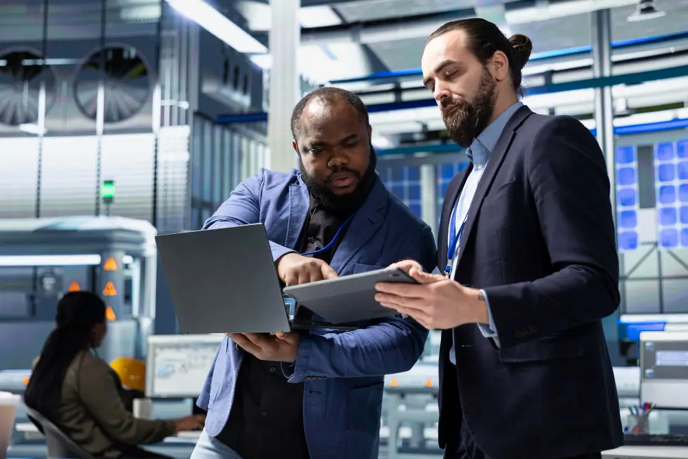 Profissionais analisando informações em laptop e tablet em ambiente corporativo